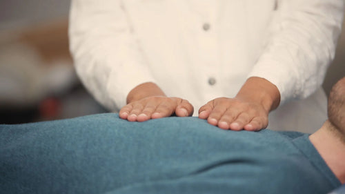 Un maître Reiki pose ses mains sur le torse d'un patient allongé