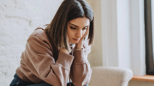 Une femme la tête entre les mains qui est pensive en raison de ses addictions