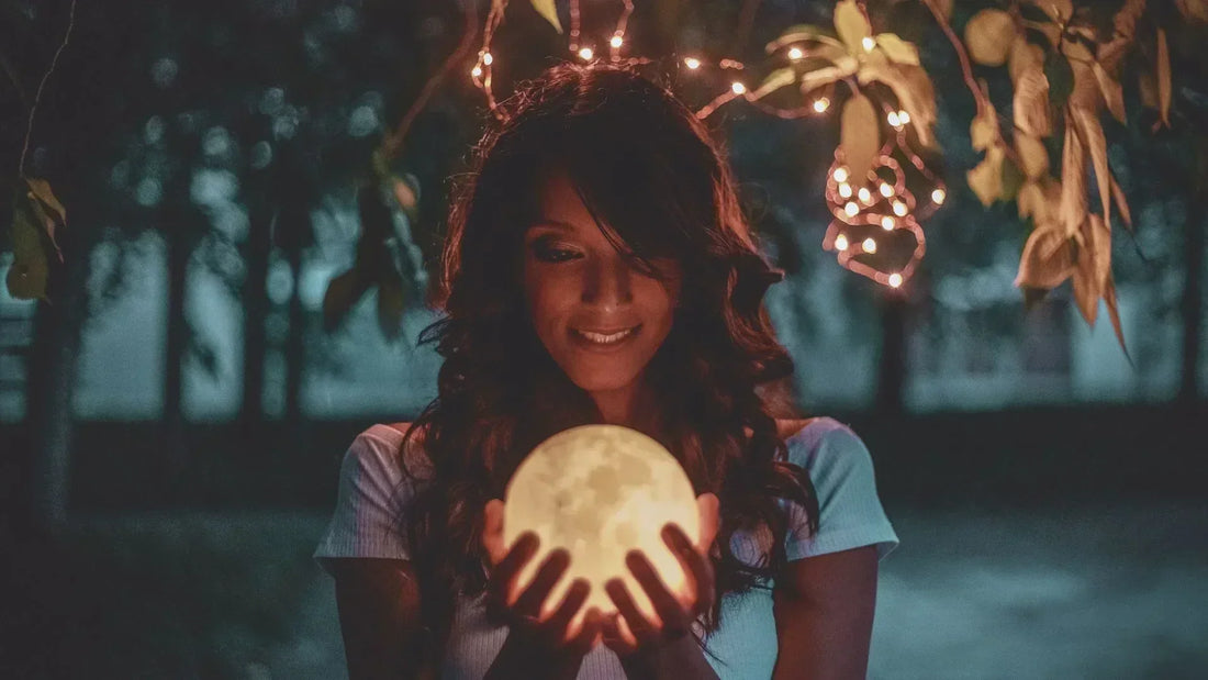 Femme tenant la nouvelle lune dans ses mains, ambiance calme et méditative.