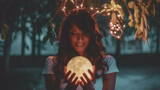 Femme tenant la nouvelle lune dans ses mains, ambiance calme et méditative.