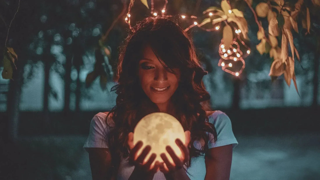 Femme tenant la nouvelle lune dans ses mains, ambiance calme et méditative.