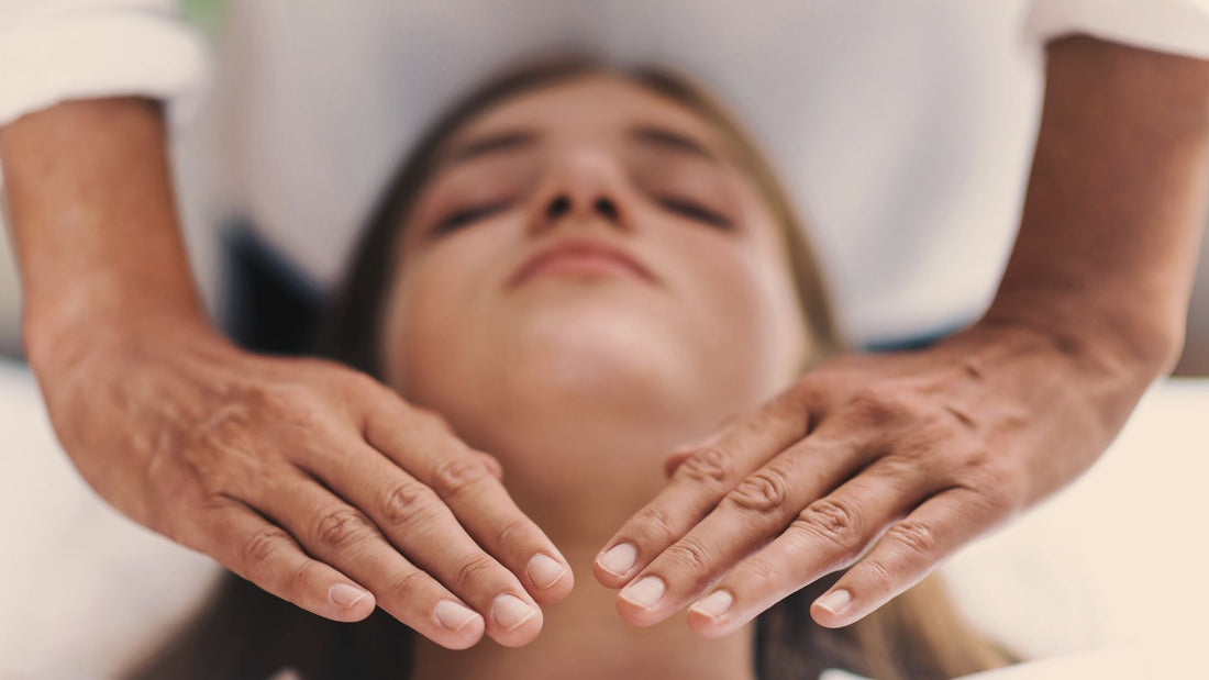 Une femme allongée avec les yeux fermés et un maitre Reiki qui a ses mains posées au dessus pendant une formation Reiki