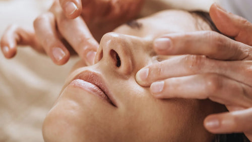 Praticien posant ses mains sur le visage d’une patiente lors d’un soin énergétique inspiré de la médecine chinoise, dans une atmosphère calme et naturelle.