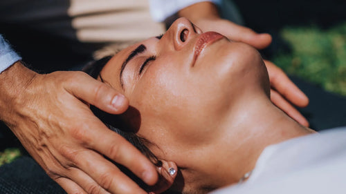 Femme allongée sur une table de soin, recevant un soin Reiki dans une ambiance apaisante, lumière tamisée, atmosphère de calme et de recentrage énergétique.